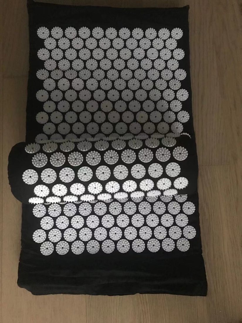 Customer photo of the black acupressure mat and pillow set on a wood floor